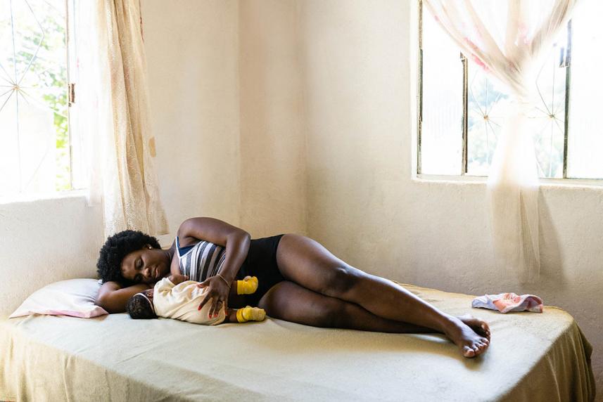 Woman lying on bed with her baby