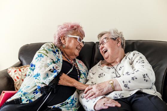 Two elderly women laughing on couch