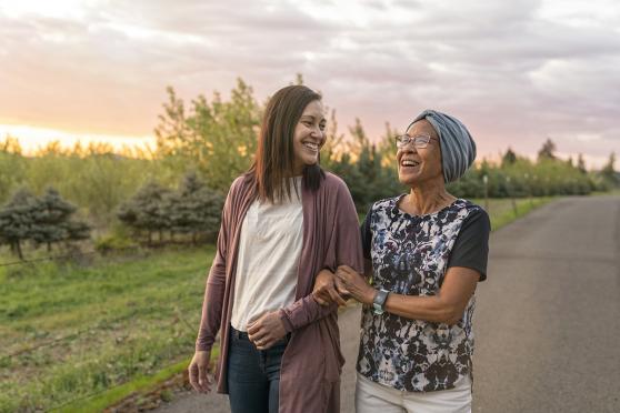 Woman walking arm in arm with older woman outdoors